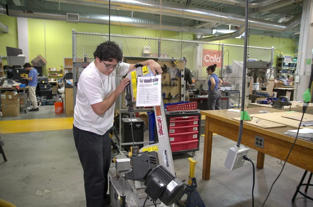 Members using the band saw in the machine shop