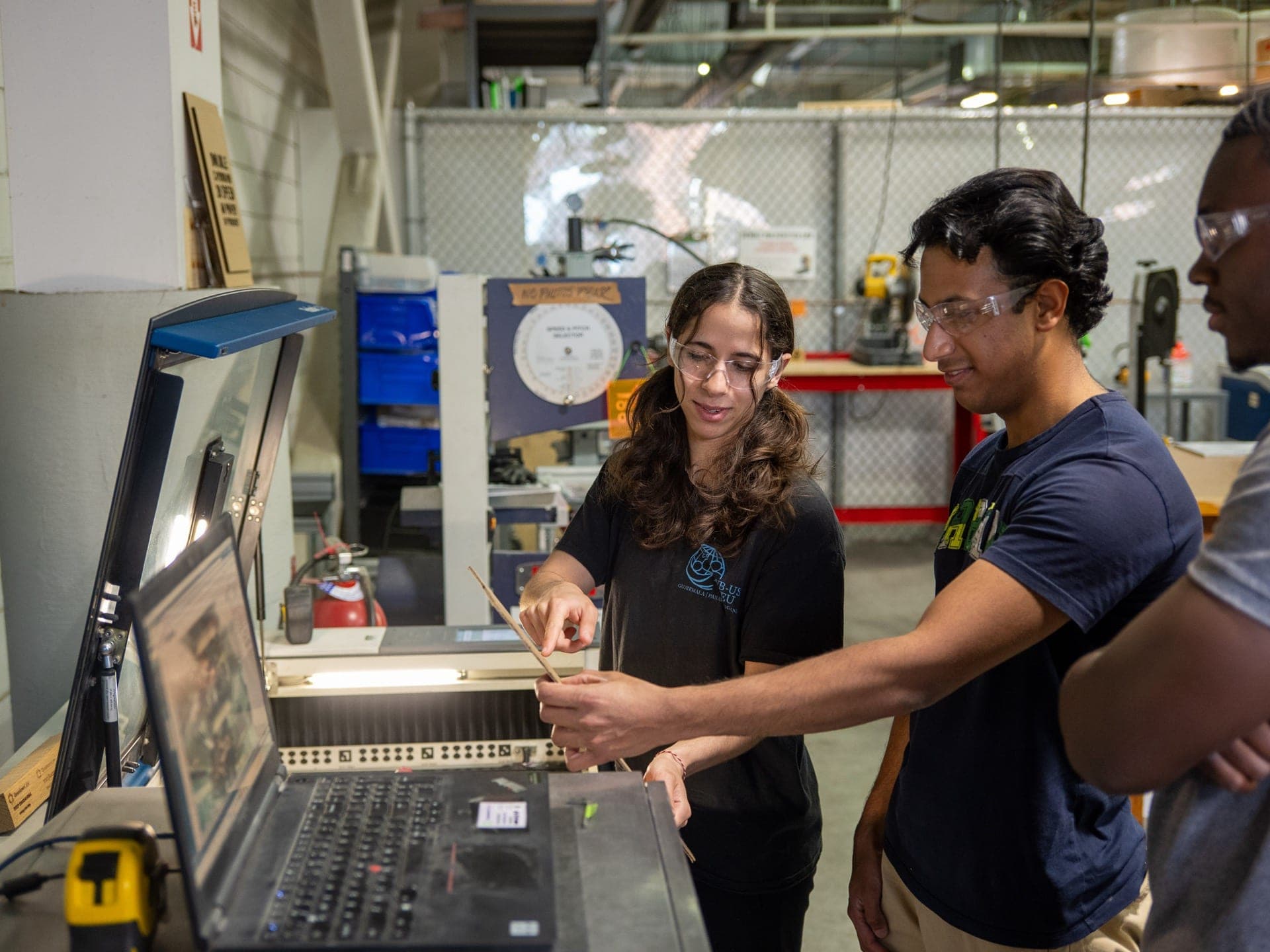 Members reviewing a CNC toolpath on a laptop in the machine shop