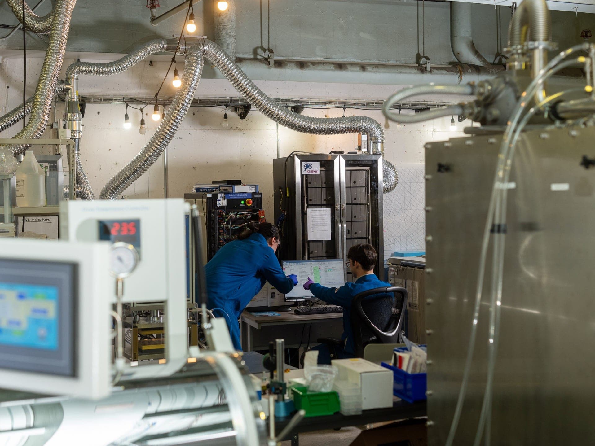 Members reviewing test data next to lab equipment in the prototyping lab