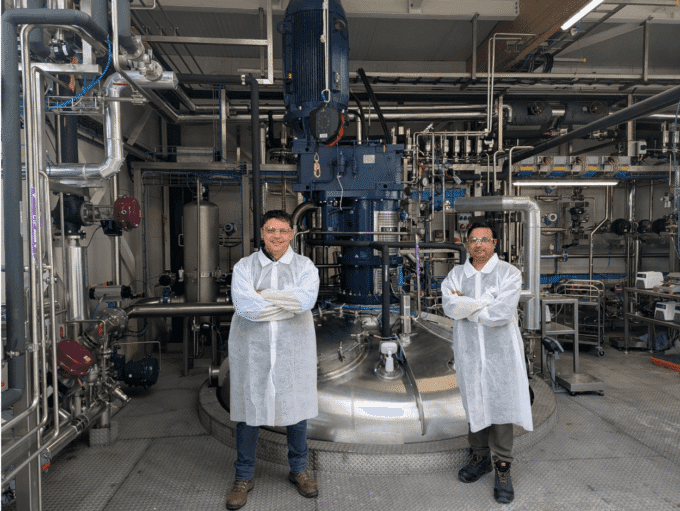 Cemvita team members standing in front of a bioreactor at their pilot plant